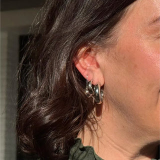 Woman wearing chunky silver hoop earrings, close up on ear, elegant jewelry style