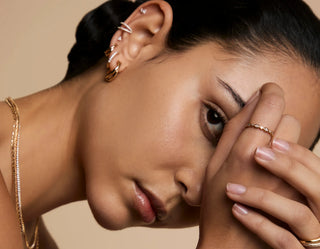 Woman wearing gold earrings, layered necklaces, and diamond ring, showcasing elegant bridal jewelry